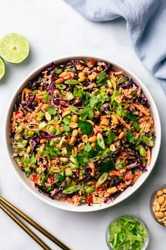 a white bowl filled with salad next to some chopsticks and lime wedges