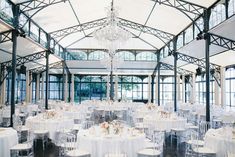 the inside of a building with tables and chairs set up for a formal dinner or party