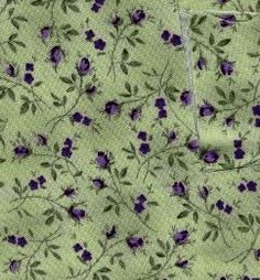 the fabric is green with purple flowers and leaves on it's side, as well as