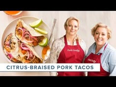 two women in aprons standing next to a plate of food