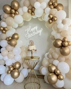 a white and gold birthday cake surrounded by balloons