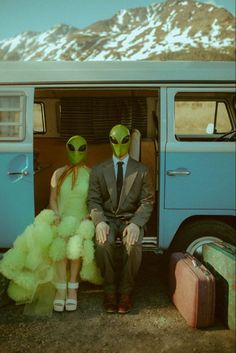 two people in alien costumes sitting next to an old vw bus