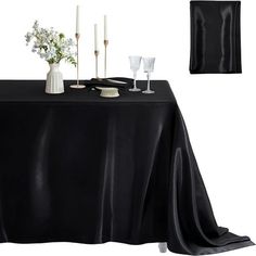 a black table cloth with candles and vases on it, along with two napkins