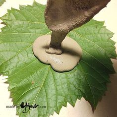 a figurine is placed on top of a leaf shaped object that looks like an elephant's foot