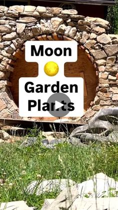 a sign that says moon garden plants in front of a stone wall and green grass