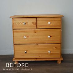 a wooden dresser sitting on top of a hard wood floor next to a white wall