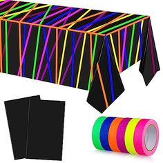 a table covered in neon colored tape next to a roll of black paper and two rolls of