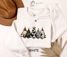 Embrace the festive spirit with our unique Holiday Cow Print Christmas Tree Sweatshirt. Featuring charming cow print Christmas trees adorned with stars and a cowboy hat, this western-themed pullover is perfect for adding a touch of country charm to your holiday celebrations. Ideal for casual gatherings or as a cozy holiday gift. Stand out this season with a blend of vintage style and holiday cheer. ### Welcome to EverCrafTees! **Handmade with Love** Ships from Texas! Shorter shipping distances a Cow Print Christmas Tree, Country Christmas Shirts, Sweatshirt Western, Retro Country, Western Cowboy Hats, Cute Christmas Tree, Cozy Holiday, Festival Shirts, Holiday Sweatshirt