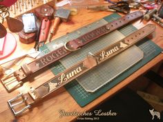 two leather belts sitting on top of a wooden table next to scissors and other items