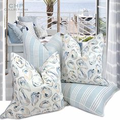 the pillows on the couch are blue and white, with an ocean view behind them