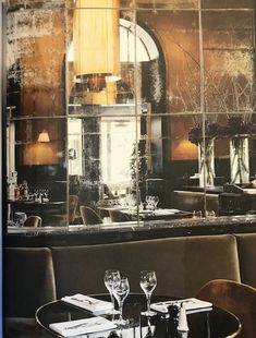 an empty restaurant with tables and chairs in front of a large glass window that reflects the interior