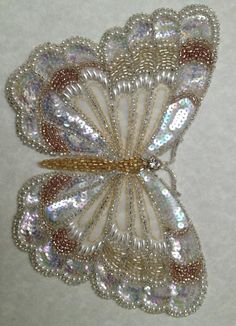 a white and gold brooch sitting on top of a table next to a wall