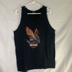 an old harley davidson tank top hanging on a hanger in front of a white sheet