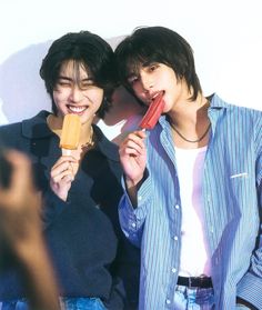 two young men eating ice cream and one is holding an orange popsicle in his hand