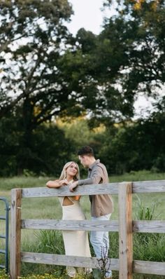 a man and woman standing next to each other near a fence