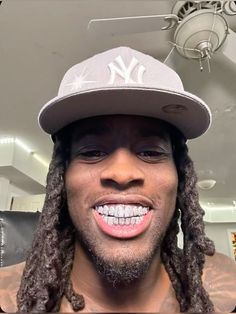 a man with dreads and a new york yankees cap on his head is smiling at the camera