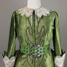 a green dress with white lace trims and buttons on the collar, along with matching gloves