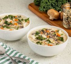 two bowls filled with soup sitting on top of a counter next to vegetables and mushrooms