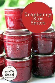 cranberry rum sauce in small glass jars on a white surface with the words cranberry rum sauce above it