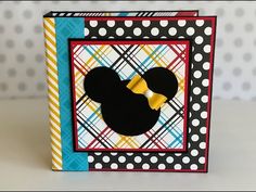 a mickey mouse card with polka dots and a yellow bow on the front, sitting on a table