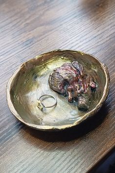 a ring sits in a bowl on a wooden table