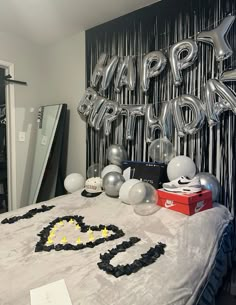 a bed topped with balloons and decorations next to a wall that says happy birthday on it