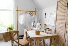 a wooden table sitting in front of a window with clothes hanging on the rack above it