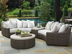 an outdoor living room with furniture and plants on the patio area next to a swimming pool