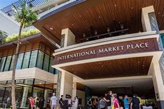 people are standing in front of the international market place building with palm trees around it