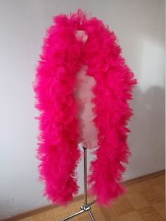 a pink feather boa on a mannequin stand in front of a white wall