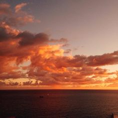 the sun is setting over the ocean with clouds