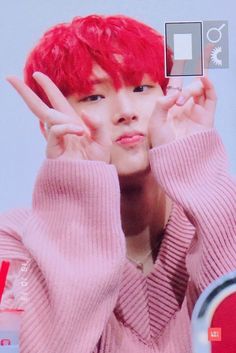 a person with red hair making the peace sign