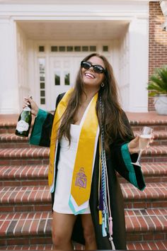 a woman in sunglasses and a graduation gown is standing on the steps