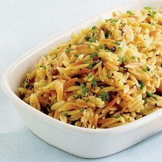 a white dish filled with pasta and garnished with parsley