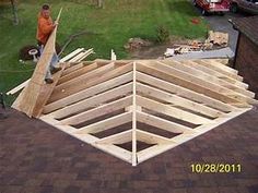 a man standing on top of a wooden roof in the middle of a yard next to a house