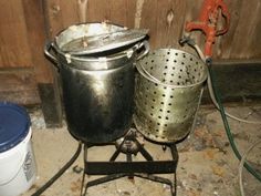 two pots sitting on top of an old stove next to a bucket and a wrench