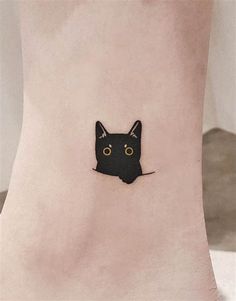 a small black cat tattoo on the side of a foot, with eyes and ears