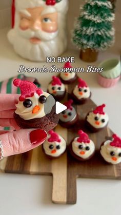 a person is holding a cupcake with frosting on it and decorated as santa claus