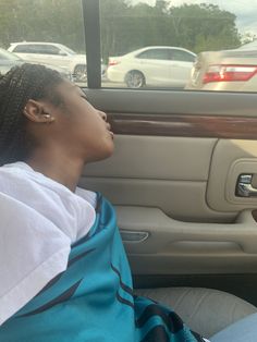 a woman sitting in the passenger seat of a car with her head out the window