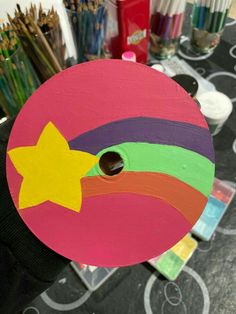 a person holding up a painted circular object with a star on the center and rainbow colors