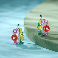 These earrings are cast from sterling silver in the shape of softly bloosm flowers. They're outlined with colorful enamel and dotted with white stones to emphasize the unique shape. These earrings are the epitome of springtime! Perfect for a fairy.Carat Weight: 0.586 ctStone Size: 1,1.7,2 mmNumber of Stones: 40 Stone Shape: RoundStone Color: Diamond WhiteWeight: 5.28 gWidth: 12.6 mmHeight: 18.9 mmThickness: 15.7 mmMaterial: 925 SilverStone Type: Jeulia® StonePlating Color: Silver Elegant Silver Enamel Flower Earrings, Enamel Flower Charm Earrings, Enamel Flower Earrings With Flower Charm, Silver Flower Enamel Earrings, Silver Enamel Flower Earrings For Pierced Ears, Silver Flower Earrings With Enamel For Pierced Ears, Silver Enamel Flower Earrings As Gift, Multicolor Enamel Flower Earrings, Multicolor Flower Enamel Earrings