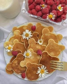 some pancakes and raspberries are arranged on a plate with a fork in front of them