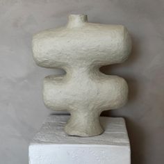 a white sculpture sitting on top of a cement block