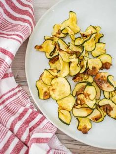 sliced zucchini on a white plate next to a red and white dish towel