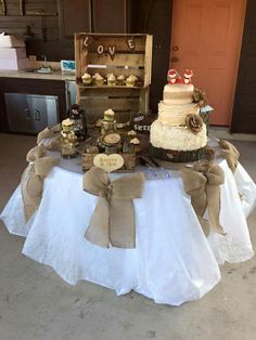 a table topped with a cake and cupcakes covered in burlap ribbon