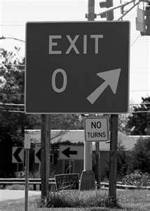 black and white photograph of an exit sign with no turns on the left hand side