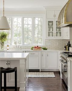 a kitchen with white cabinets and counter tops, along with an island in the middle