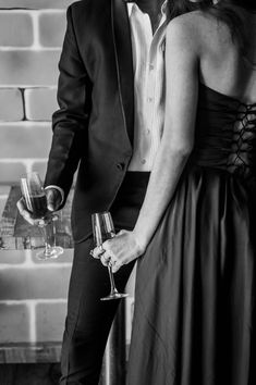 a man and woman standing next to each other with wine glasses in front of them