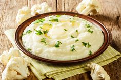 mashed cauliflower with parsley in a brown bowl on a wooden table