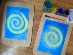 two wooden frames with blue and green swirls on them next to paintbrushes